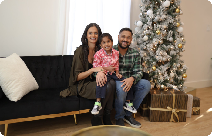 A family sitting on the couch in front of a christmas tree.