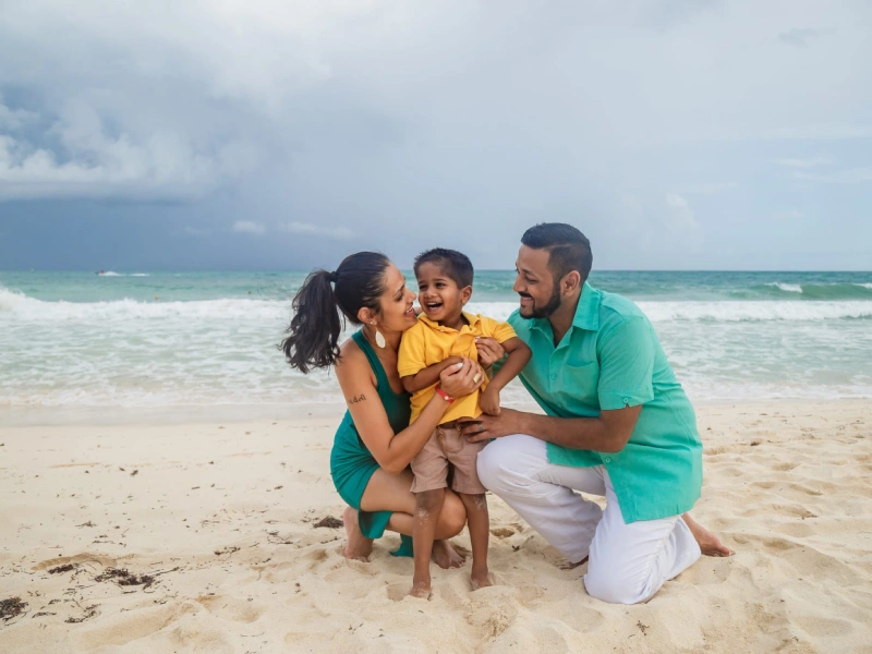 A family sitting on the beach with one child